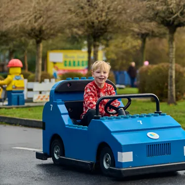 Boy in Christmas jumper driving a blue car at LEGO City Driving School