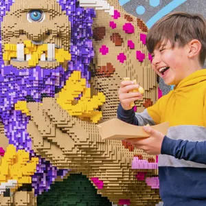 Boy eating chips next to a LEGO model of a troll outside The Hungry Troll restaurant