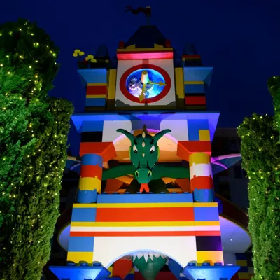 Ollie the Dragon model in the Clocktower outside of the LEGOLAND Resort Hotel against a night sky backdrop with fiary lights in the trees