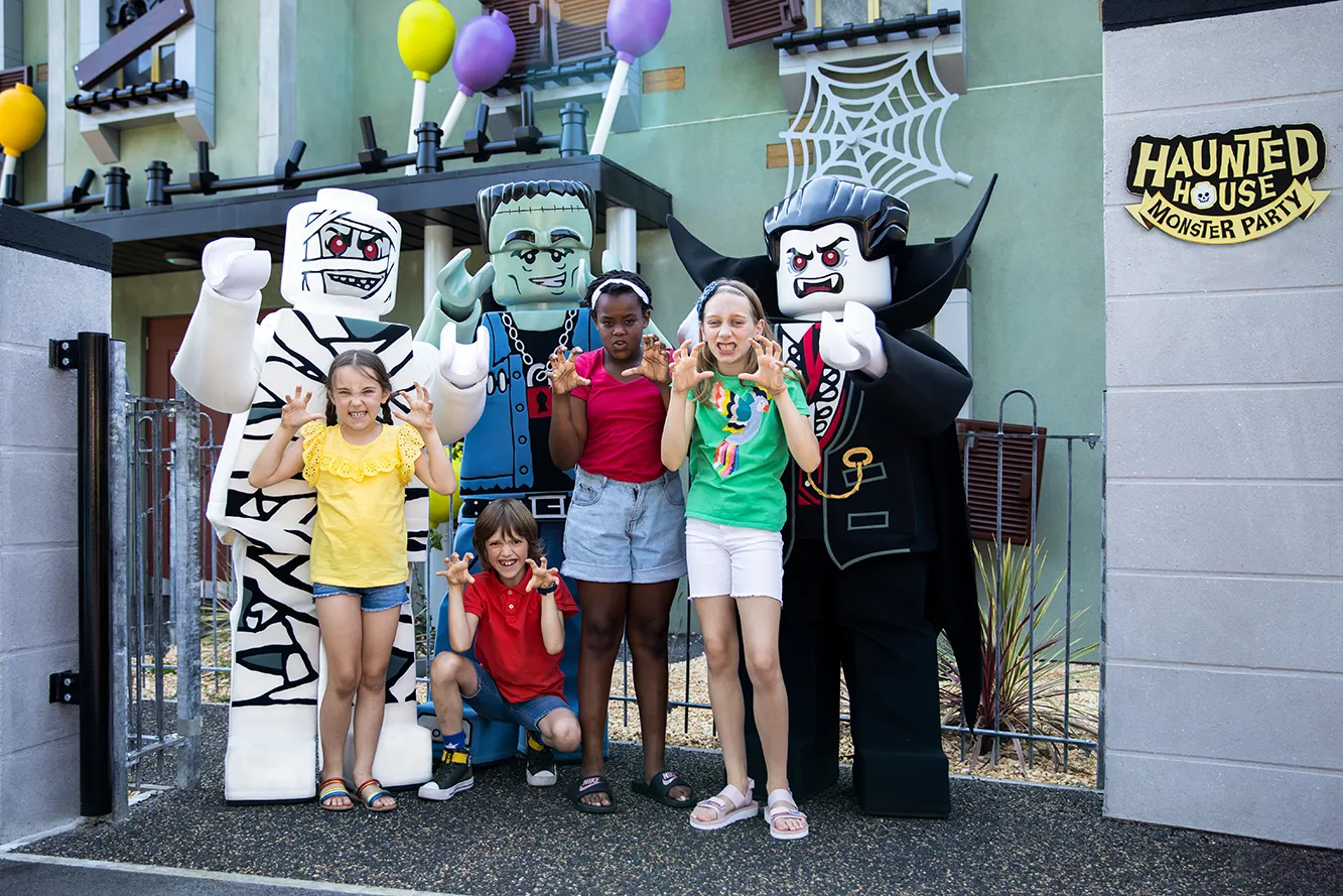 Lord Vampyre and Monster Friends with children pulling scary faces outside Haunted House Monster Party at LEGOLAND® Windsor Resort