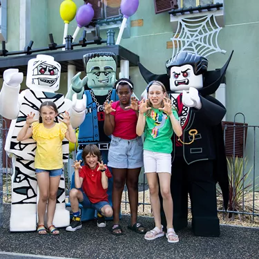 Lord Vampyre and Monster Friends with children pulling scary faces outside Haunted House Monster Party at LEGOLAND® Windsor Resort