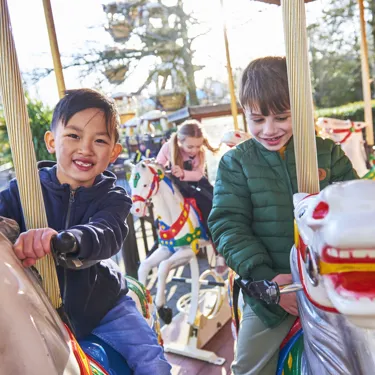 Boys smiling while riding Desert Chase carousel