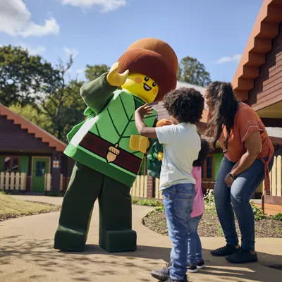 Forest Elf meeting family outside of a Standard Lodge in the LEGOLAND Woodland Village