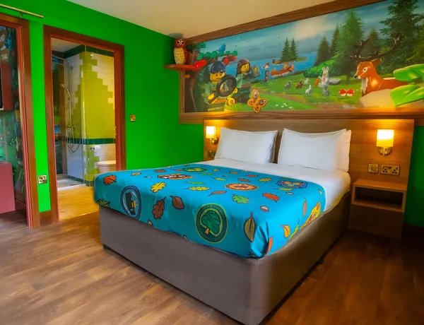 The interior of a Woodland Village Standard Lodge, including double bed, separate children's sleeping area and bathroom at LEGOLAND Windsor