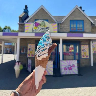 Ice Cream in a cone with chocolate sauce and blue sprinkles in the sun, outside of the Ice Cream Parlour