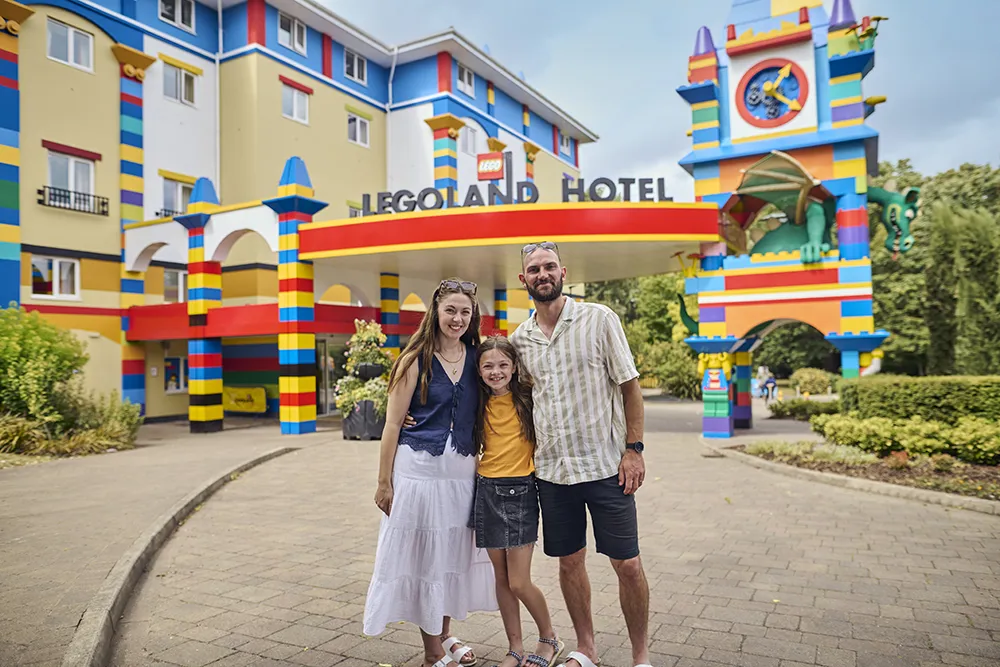 Mother, father and daughter smiling outside the entrance of the LEGOLAND Resort Hotel