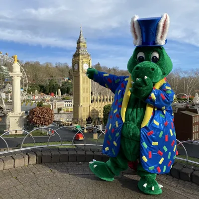 Ollie the Dragon with Easter bunny ears and LEGO print shiny coat in front of the London area of Miniland
