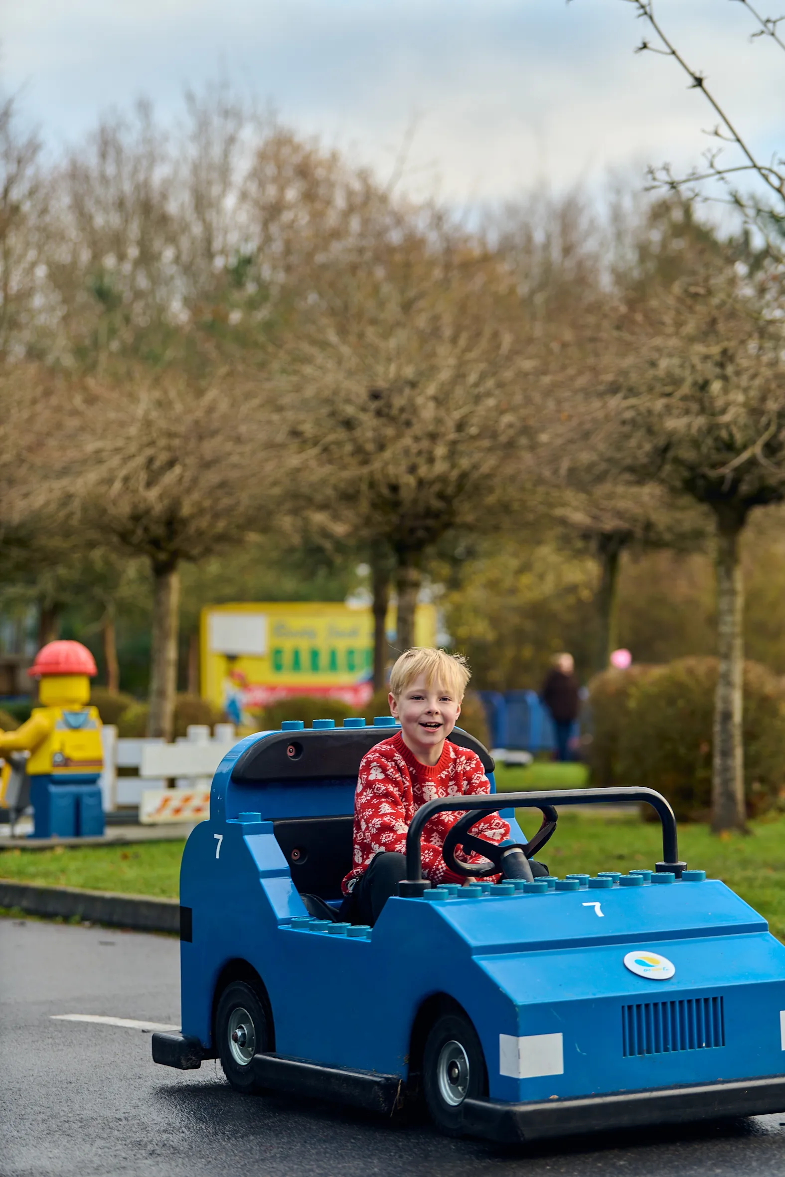 Boy in a Christmas jumper in a blue LEGO car