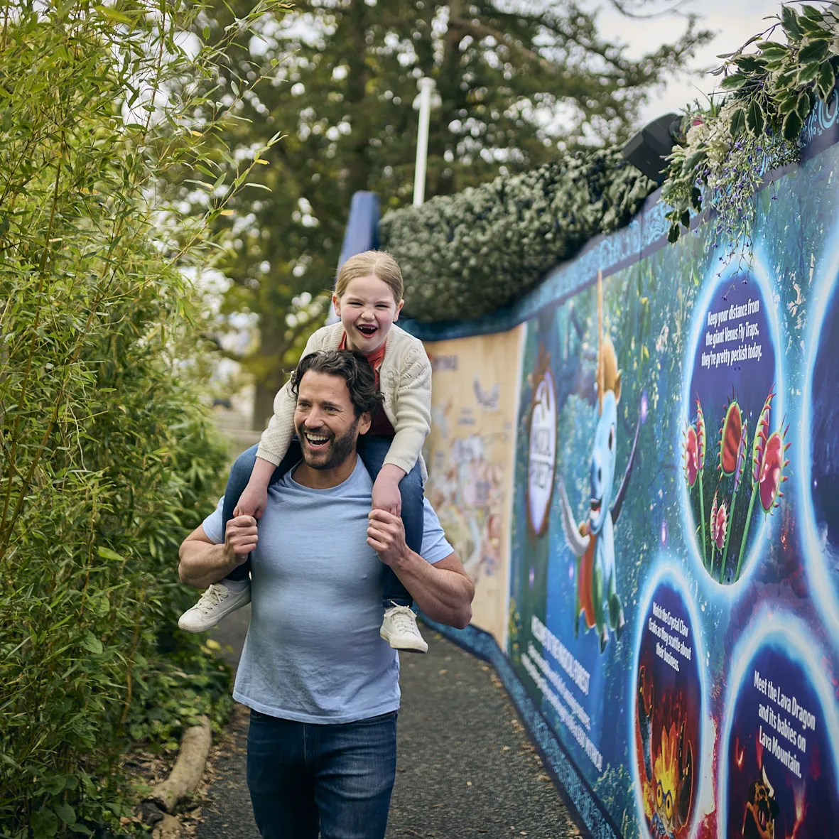 Young girl on Dad's shoulders walking through The Magical Forest