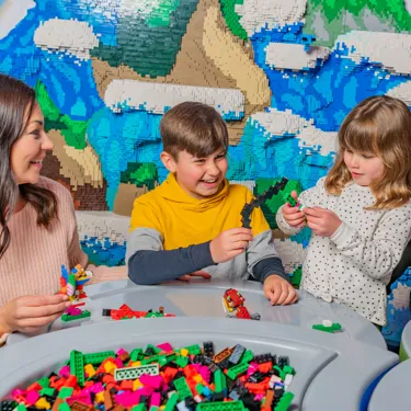 Mother and children building mythical creatures out of LEGO in Creature Creation