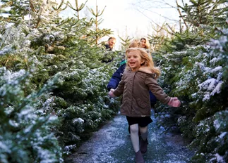 Girl smiling and running through snow covered trees at LEGOLAND at Christmas at the LEGOLAND Windsor Resort