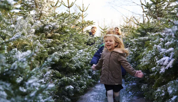 Girl smiling and running through snow covered trees at LEGOLAND at Christmas at the LEGOLAND Windsor Resort