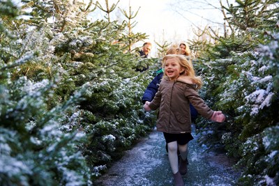 Girl smiling and running through snow covered trees at LEGOLAND at Christmas at the LEGOLAND Windsor Resort