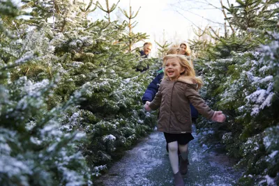 Girl smiling and running through snow covered trees at LEGOLAND at Christmas at the LEGOLAND Windsor Resort