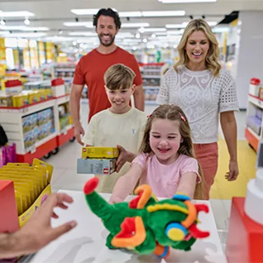 Family with girl handing over Ollie the Dragon plush toy at the till in The LEGO Store