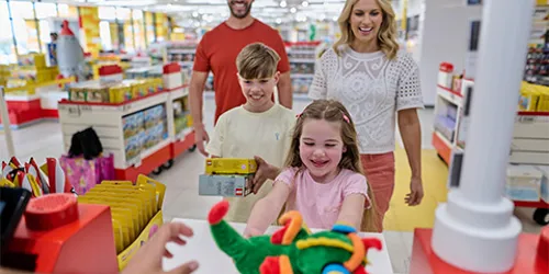 Family with girl handing over Ollie the Dragon plush toy at the till in The LEGO Store