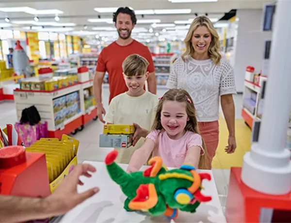 Family with girl handing over Ollie the Dragon plush toy at the till in The LEGO Store