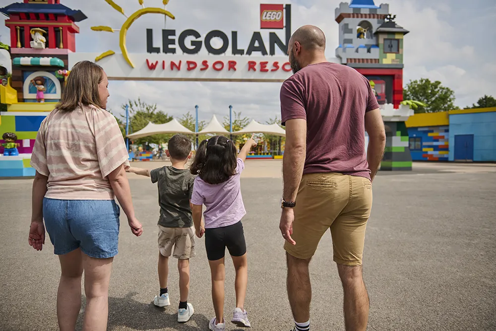 Family entering the LEGOLAND Windsor Resort underneath the LEGO-themed entrance portal