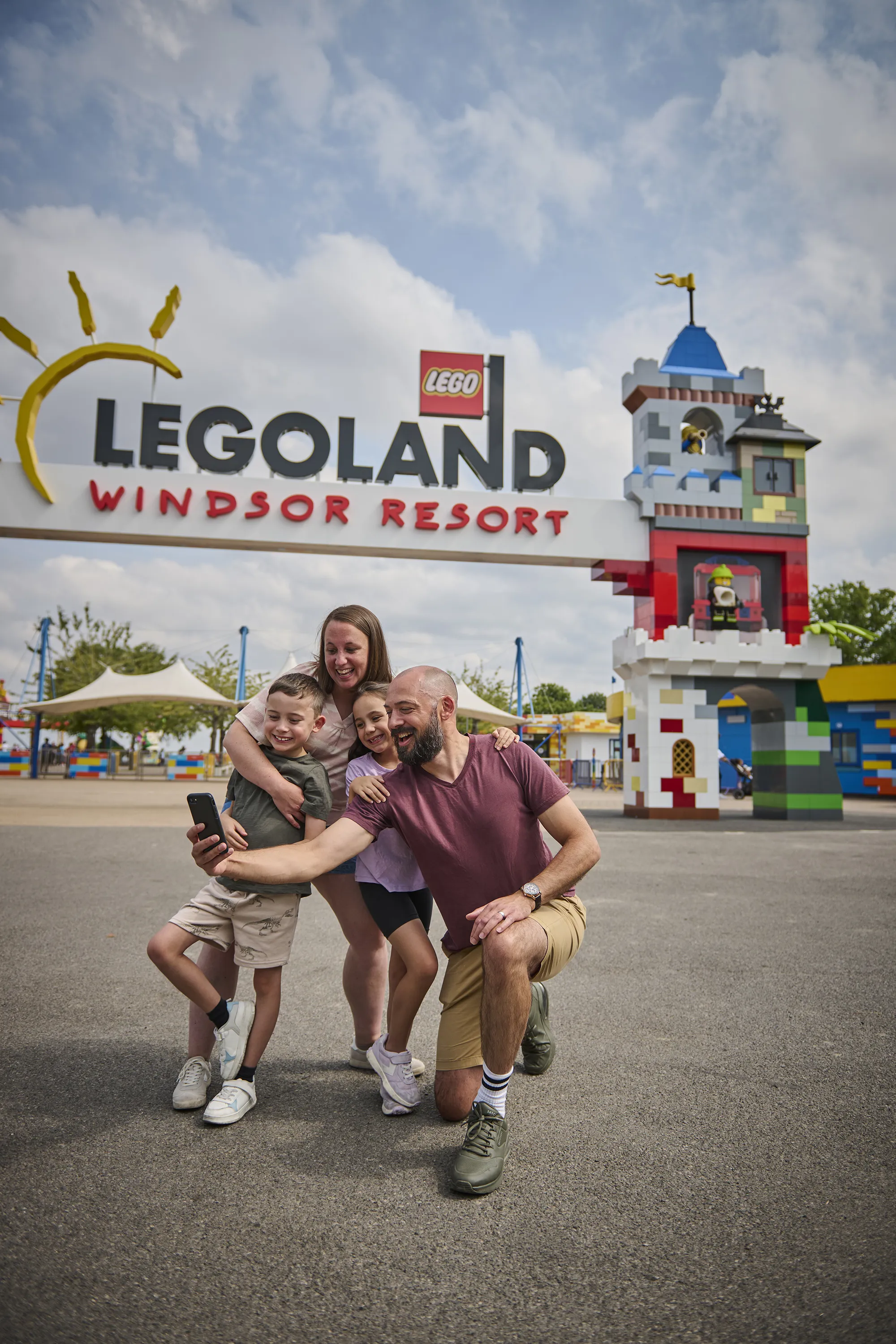 Family taking selfie outside of LEGOLAND Windsor Resort with the LEGO-themed portal in the background