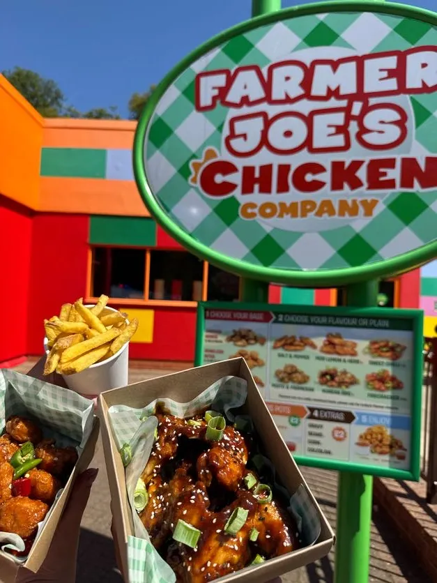 Farmer Joe's Chicken Shop Sign in the background of 2 chicken based meal boxes and a portion of chips