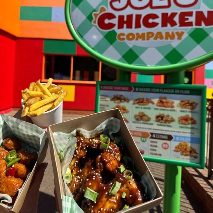 Farmer Joe's Chicken Shop Sign in the background of 2 chicken based meal boxes and a portion of chips