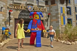 Two children meeting Jester minifigure character outside of the LEGOLAND Castle Hotel