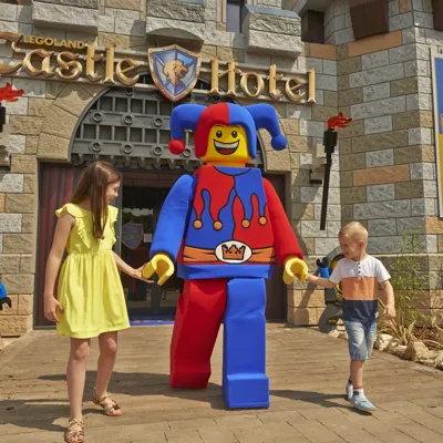 Two children meeting Jester minifigure character outside of the LEGOLAND Castle Hotel