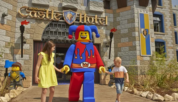 Two children meeting Jester minifigure character outside of the LEGOLAND Castle Hotel
