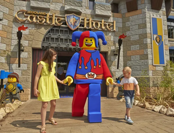 Two children meeting Jester minifigure character outside of the LEGOLAND Castle Hotel