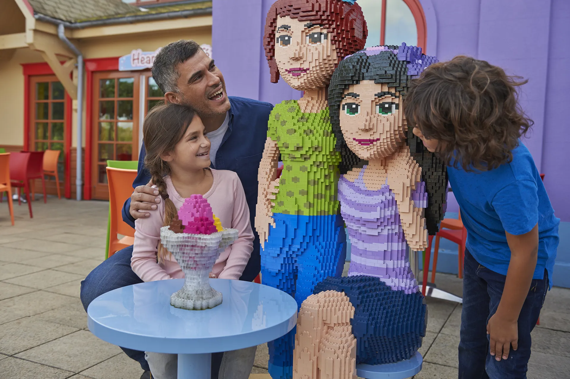 Family with LEGO Friends models outside of Heartlake Cafe