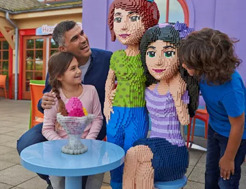 Family with LEGO Friends models outside of Heartlake Cafe