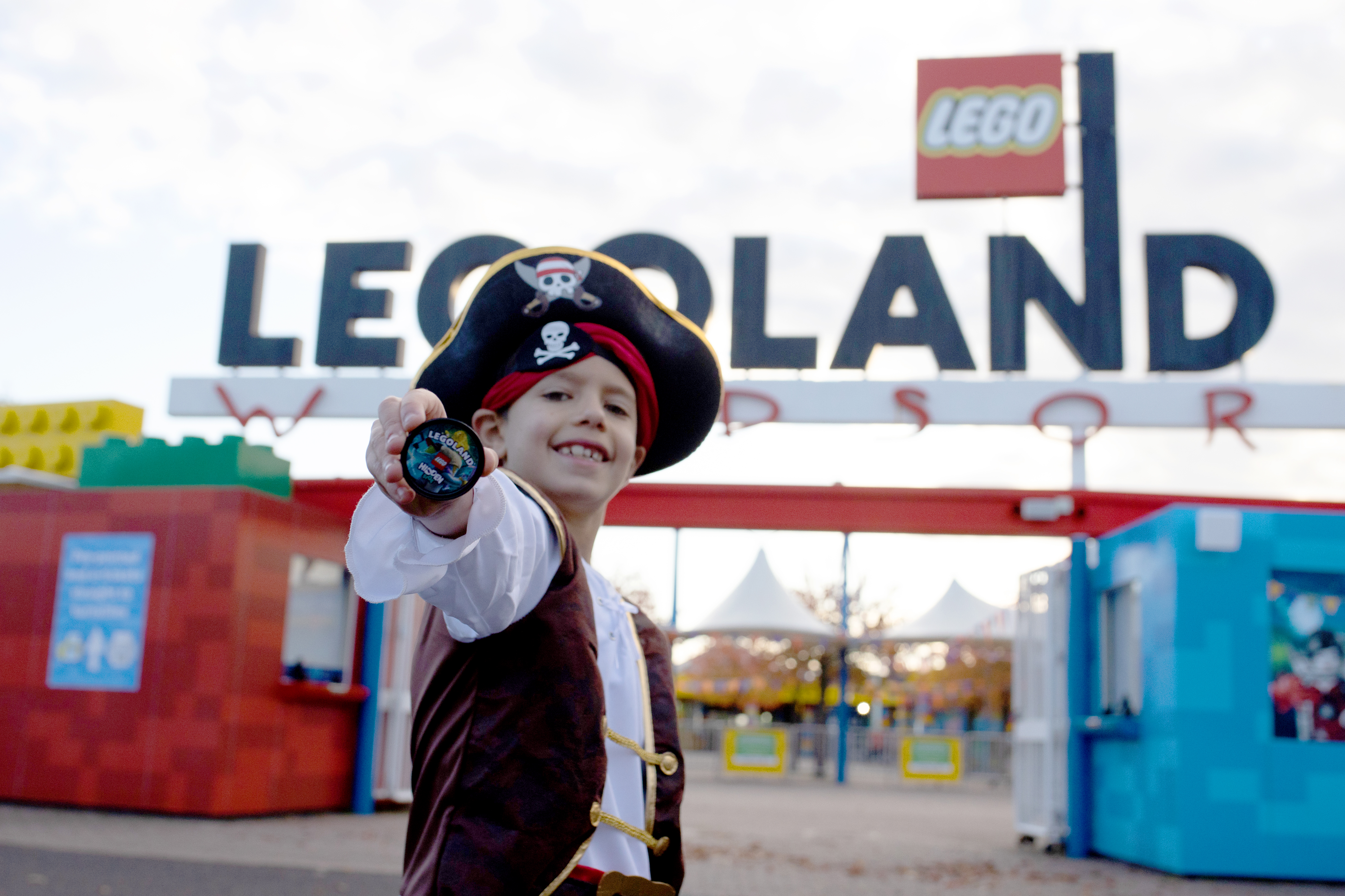 Boy in Pirate Costume holding POP Badge outside the entrance of the LEGOLAND Windsor Resort