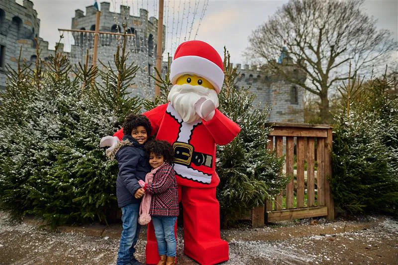 2 children smiling with LEGO Santa Minifigure character