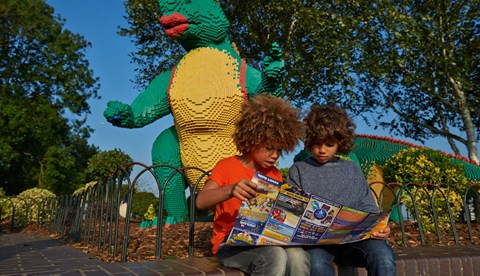 Children looking at map in front of LEGO model of a dinosaur