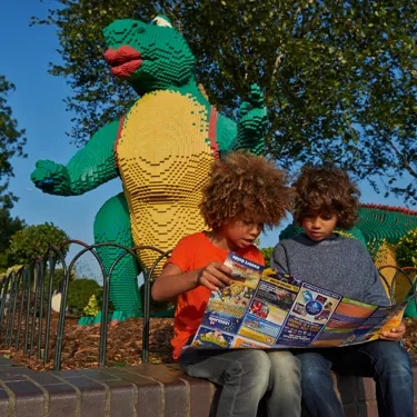Children looking at map in front of LEGO model of a dinosaur