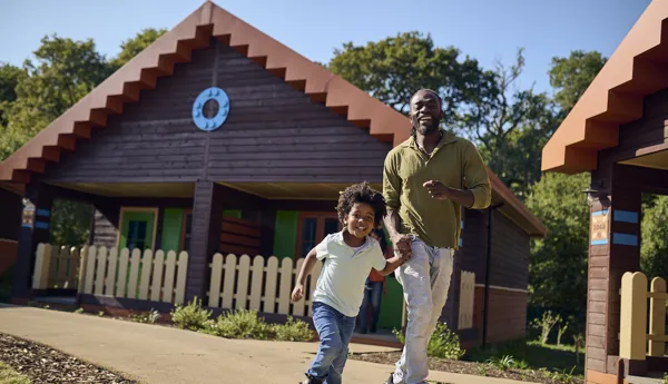 Father and son outside of a standard lodge running through the LEGOLAND Wooland Village in Windsor