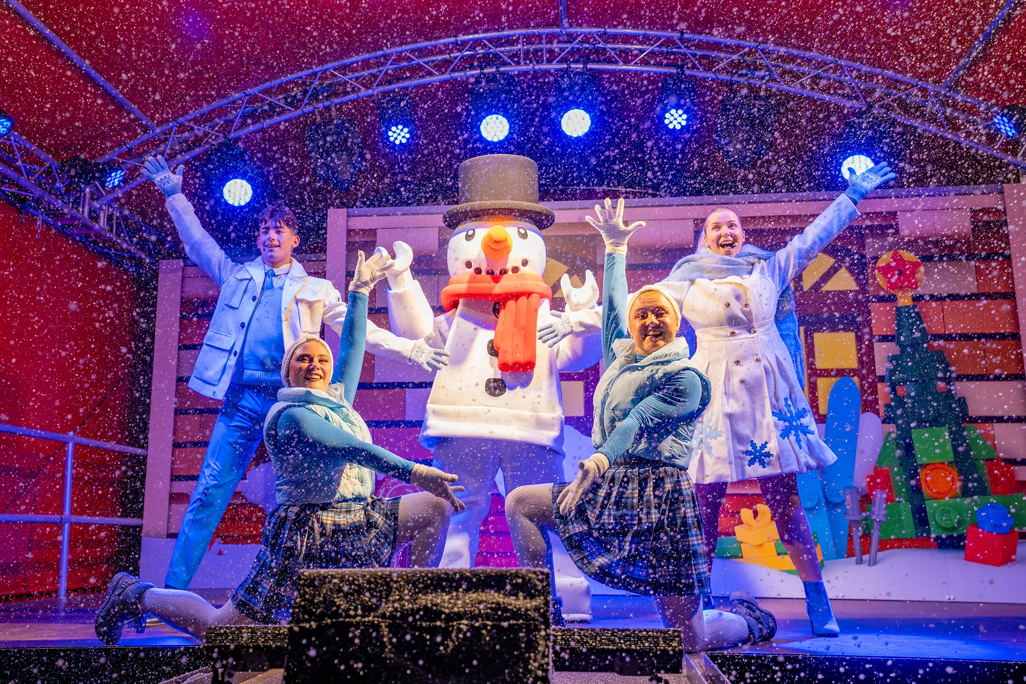Festival of Flurries Show at LEGOLAND at Christmas: Snowman minifigure with 4 dancers on a festively-decorated stage with snow