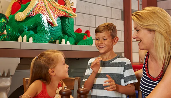 Family with menus next to a LEGO model of a dragon in Tournament Tavern restaurant in the LEGOLAND Castle Hotel