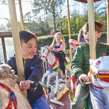 Boys smiling while riding Desert Chase carousel