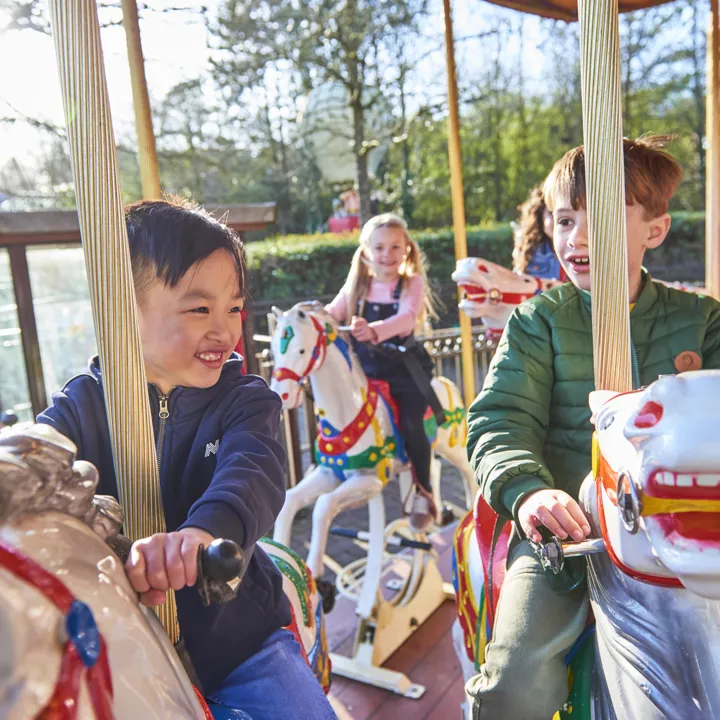 Boys smiling while riding Desert Chase carousel
