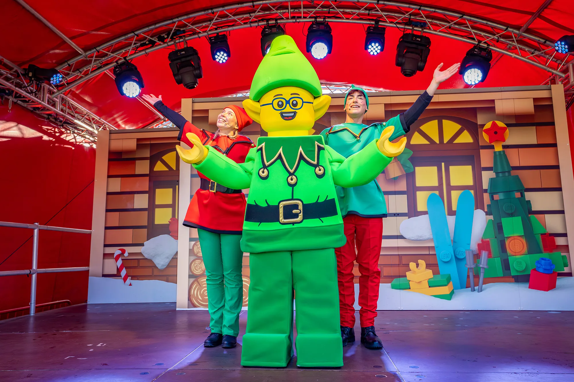 Elf Training Academy Show at LEGOLAND at Christmas: Elf Frode Minifigure with two elf dancers on a stage