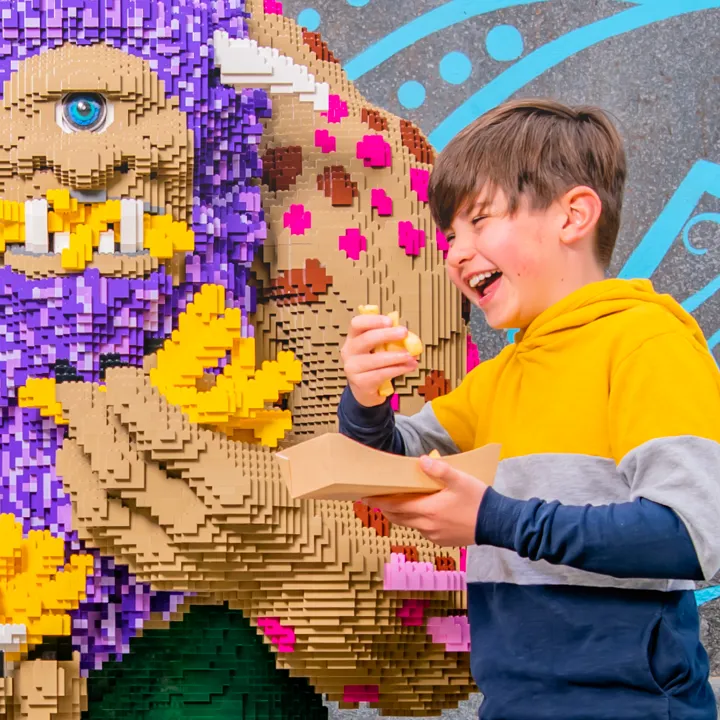 Child enjoying Chips next to LEGO® Troll at The Hungry Troll restaurant