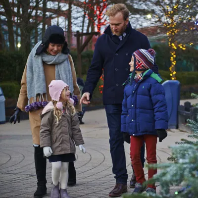 Family walking past snow covered Christmas trees and Christmas lights at LEGOLAND at Christmas