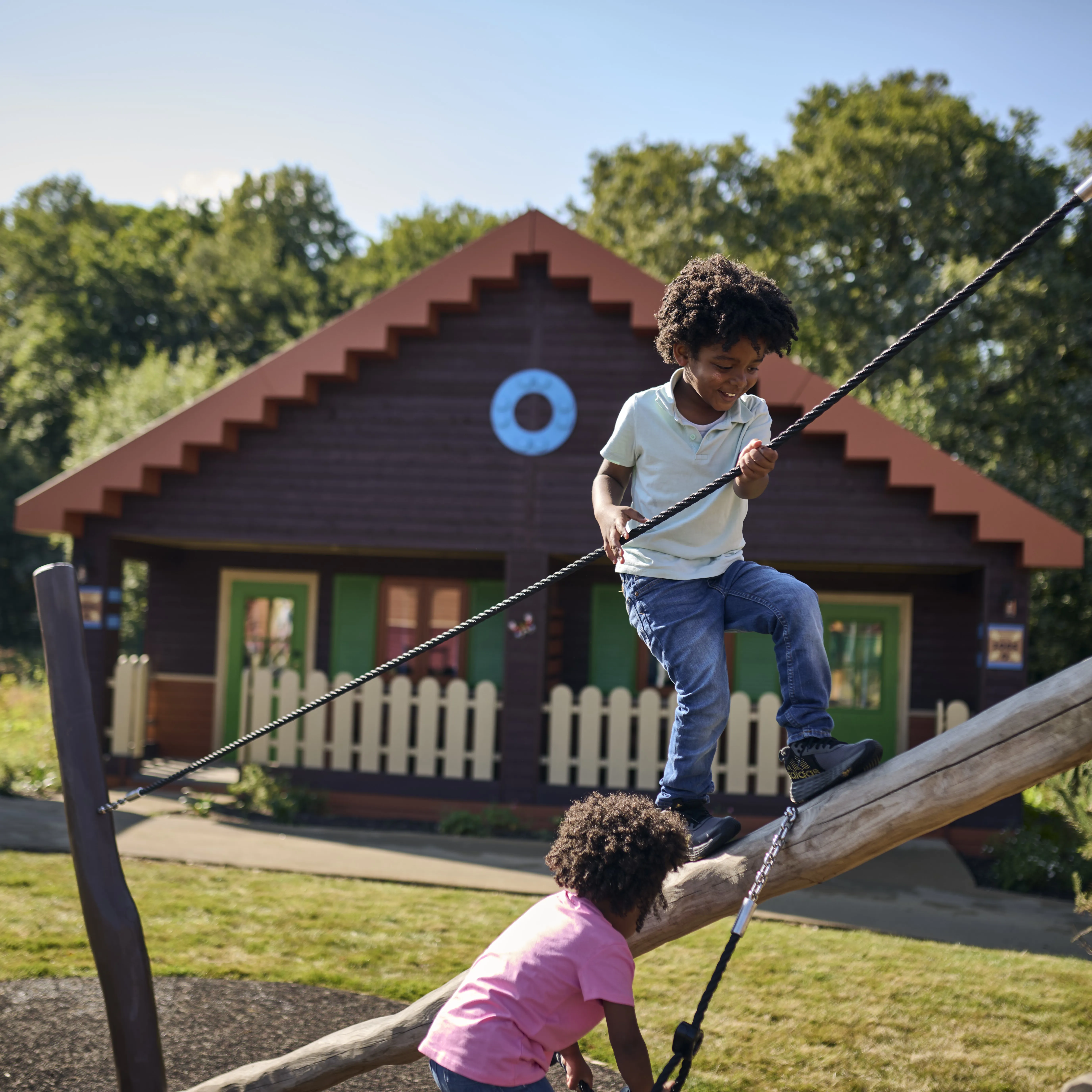 Children playing on a Woodland Village play structure outside a Woodland Lodge