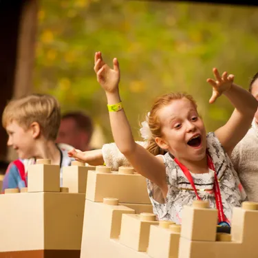 Children smiling with hands in the air on Merlin's Challenge