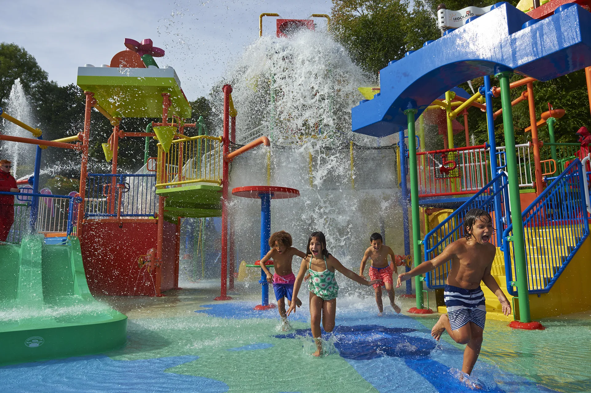 Children running from big water splash at Drench Towers