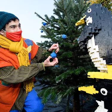 Elf hanging LEGO baubles on Christmas tree with LEGO penguins at LEGOLAND at Christmas at the LEGOLAND Windsor Resort