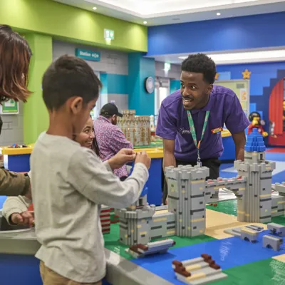 Staff member interacting with families building with LEGO in the LEGOLAND Playroom
