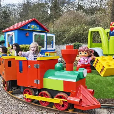 Three girls smiling and waving on DUPLO Train