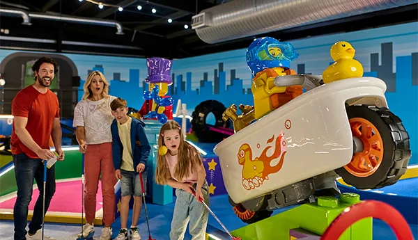 Family playing LEGO City course at LEGOLAND Adventure Golf in Windsor, the world's first indoor LEGO golf experience